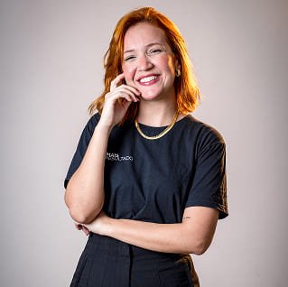 Coordenadora de mídias e atendimentos sorrindo, usando camiseta preta com o logotipo da Agência Mais Resultado, em uma sessão de fotos profissional.