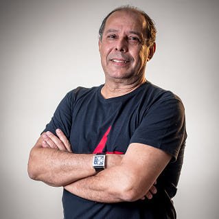 Paulo Mauricio, profissional do setor comercial e atendimento, com os braços cruzados, usando camiseta preta com estampa vermelha, em sessão de fotos na Agência Mais Resultado.